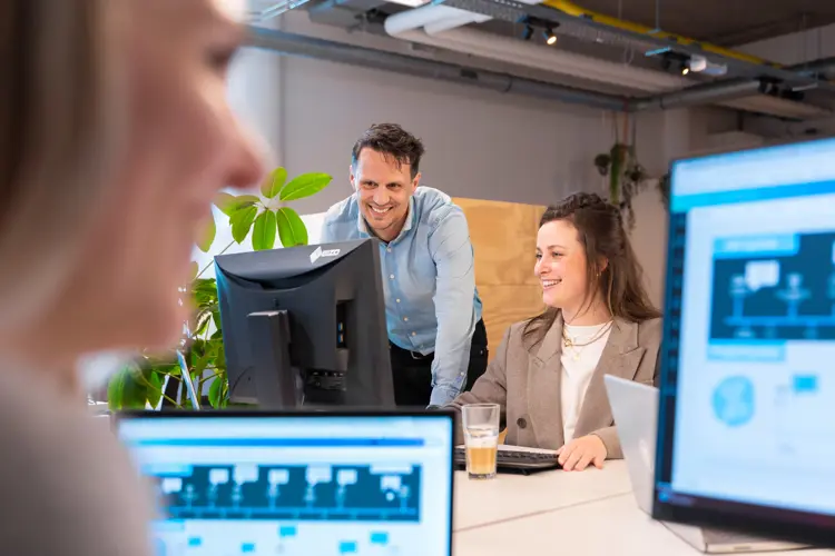 Twee Managers Van Nrg Office Kijken Samen Lachend Naar Een Computerscherm