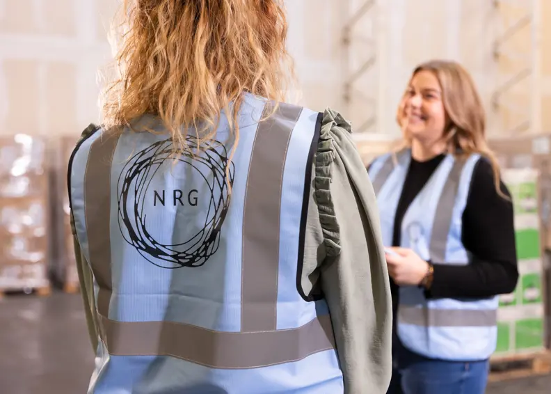 Foto Van De Achterkant Van Een Nrg Office Veiligheidshestje Van Twee Mensen In Gesprek