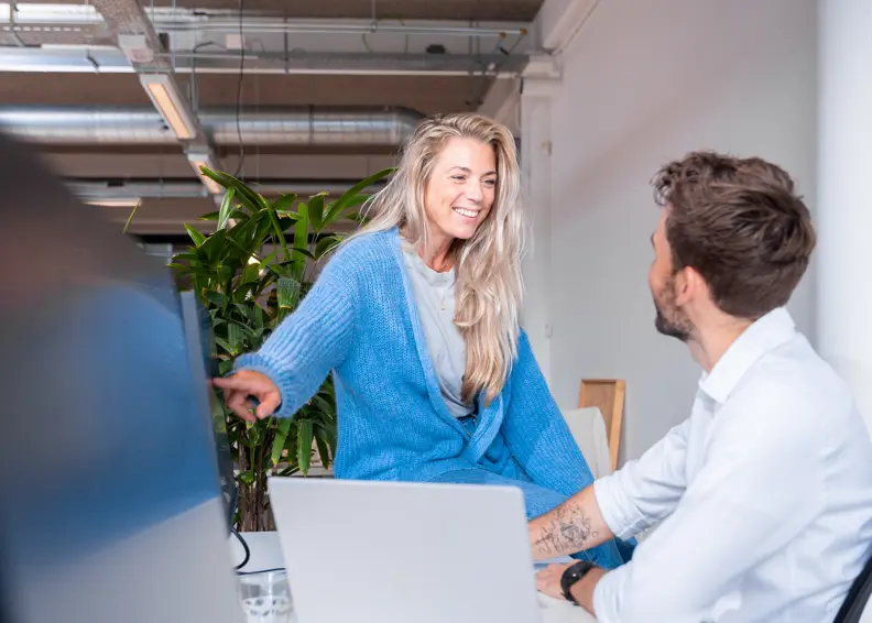 Foto Van Twee Personen Van Nrg Office In Gesprek Achter De Computer En Een Persoon Wijst Wat Aan
